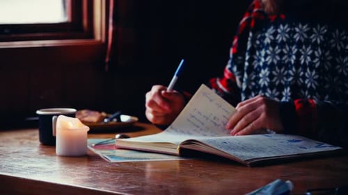 A Man Flips Through the Pages of a Journal Before Writing in it, Inside a Cozy Cabin in Reinsjøen