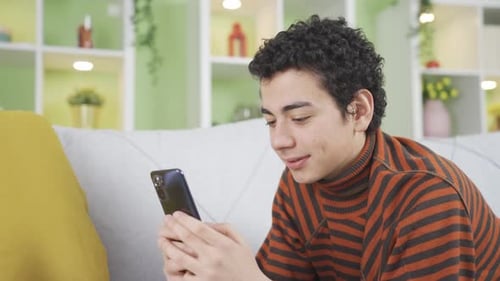 Smiling Teen Using Smartphone While Lying on Couch