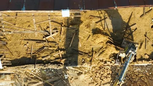 Vue de haut en bas d'une griffe d'excavatrice en train de nettoyer des débris de bois sur un chantier de construction, montrant l'arrière