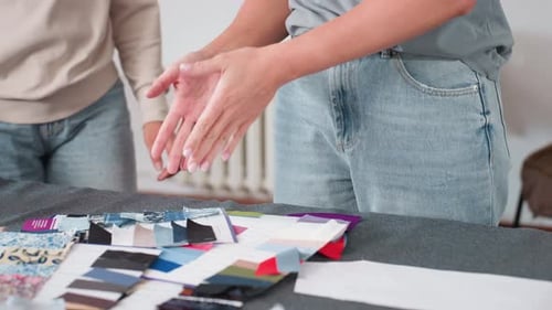 Modeschöpfer zeigt Auszubildenden verschiedene Stoffteile