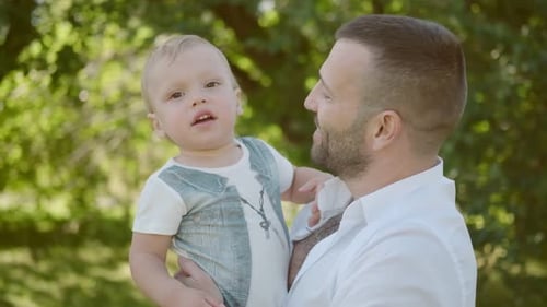 Father Holds Little Son in His Arms Dad and Son Spend Time Together Outdoors in the Park