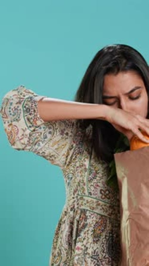 Vídeo vertical de una mujer con una bolsa de papel ecológica en las manos mirando un pimiento
