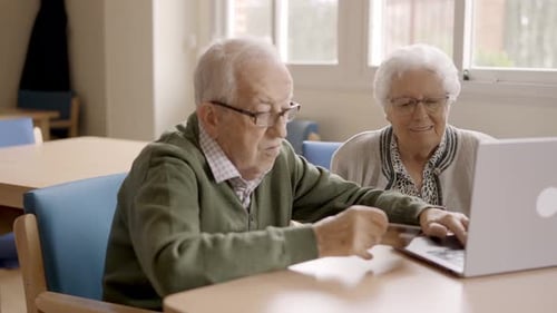 Senior Adults Using Laptop at Table Indoors