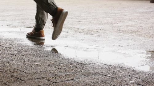 Spotting puddle under walkway, diverse senior men stepping to cross water, causing ripples