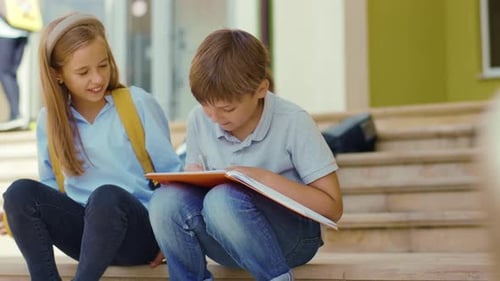 Freundschaft in der Schule Zwei süße Kinder treffen sich vor der Schule und machen gemeinsam Hausaufgaben in