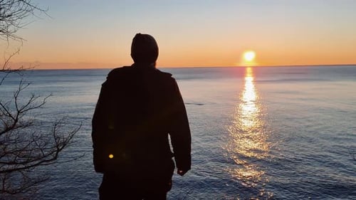 Young Man Walking on the Beach in Beautiful Sunset at the Sea Clear Sky Sun Setting Down to Horizon