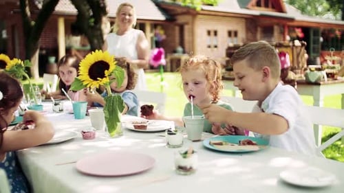 Small Children Sitting at the Table Outdoors on Garden Party in Summer,