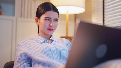 Woman Looking At Laptop On Couch At Night