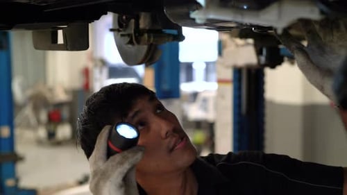 Mechanic asian man examining and service maintenance the suspension of a vehicle