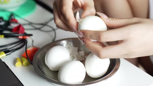Woman Peels Hard Boiled Egg at a Table