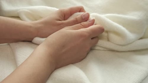 Weibliche Hand auf weißem Plüschstoff mit weichem Nickerchen