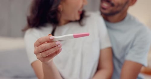 Excited Couple Holding Positive Pregnancy Test at Home