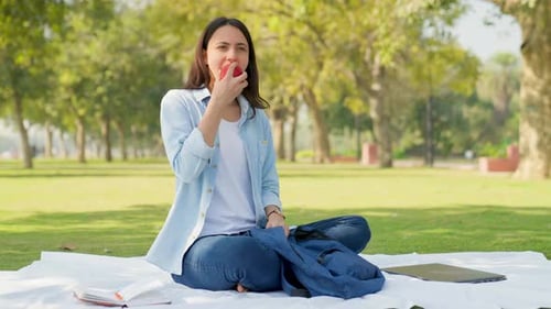 Woman Eating Apple Sitting in Park