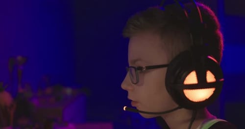 Focused Young Gamer with Headset Playing PC Games Side View