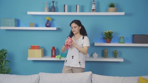 Woman Cheerfully Dusting Decorative Items in Modern Apartment