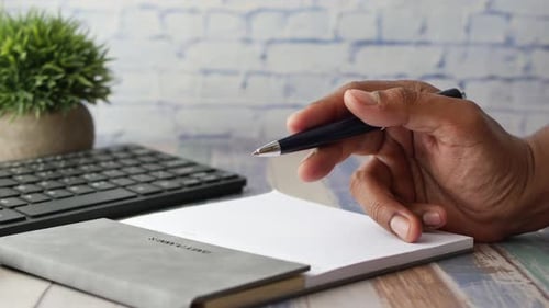 Man Hand Writing on Notepad While Sited