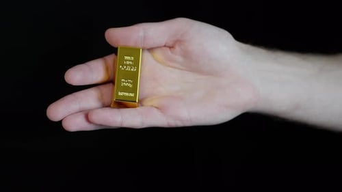 Person Holding Gold Bar Exchanges it for One Bitcoin