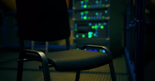 Focus on an Empty Chair in a Dimly Lit Server Room Filled with Lights