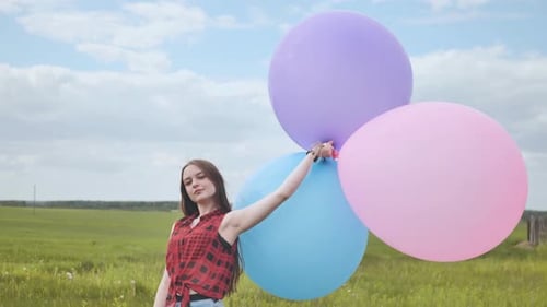 Happy Girl with Big Multicolored Balloons Posing on the Field