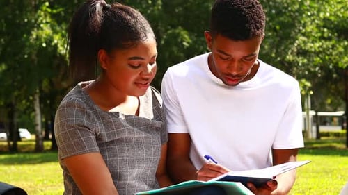 Young Two Students Sitting in Park with Books in Sunny Spring Day