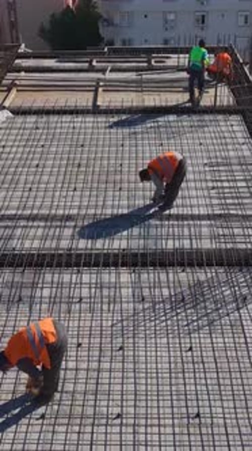 Vertical Video Aerial View of a Construction Site With Workers Preparing New Floors and Installing
