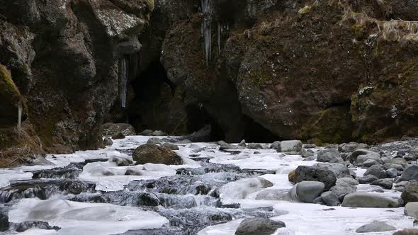 A river flowing over snow and ice covered rocks as it leaves a ravine ...