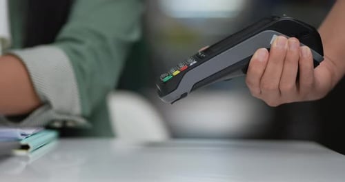 Client using credit card machine for non cash payment in cafe.