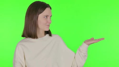 Junge Frau zeigt sich auf der Seite auf grünem Hintergrund