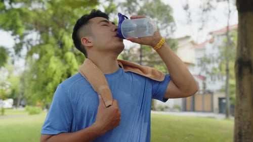 Man Drinking Water in City Park after Training