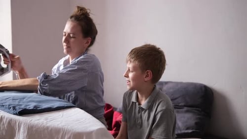 Woman Ironing Clothes with Child Watching