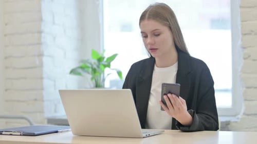 Woman Works at Desk with Laptop and Phone