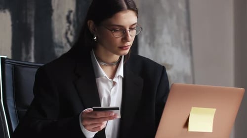 Pretty Girl is Making Online Payment Holding Bank Card Using Modern Laptop at Home or Office Finance