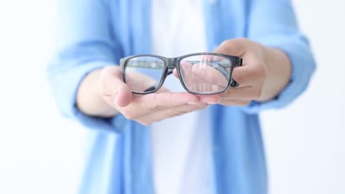 Woman showing pair of glasses on white background, closeup