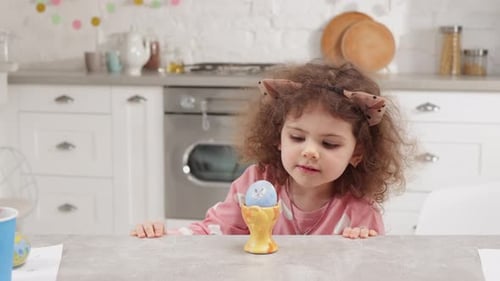 Cute Child Looks at Decorated Easter Egg