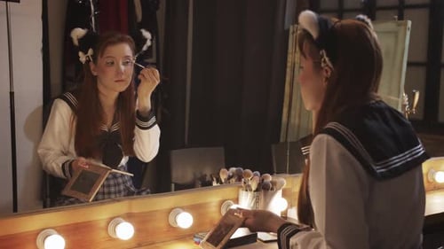 Woman Applies Makeup in Front of Mirror