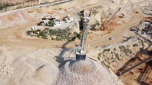 large Quarry during work hours with Stone sorting conveyor belts and an open pit mine.