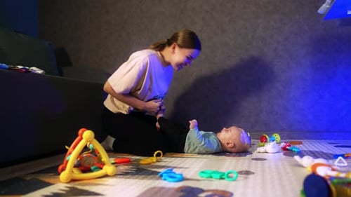 Mother playing with baby on playmat indoors