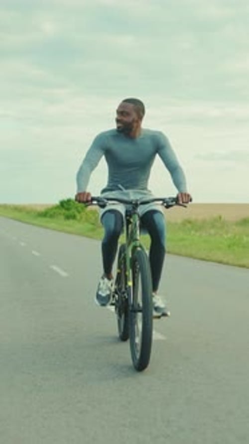 A Man is Riding a Bicycle Down a Long and Winding Road Ahead