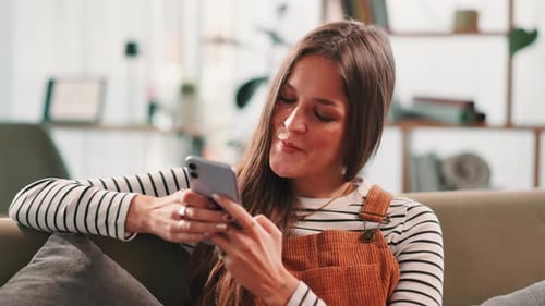 Woman Using Mobile Phone While Relaxing on Couch
