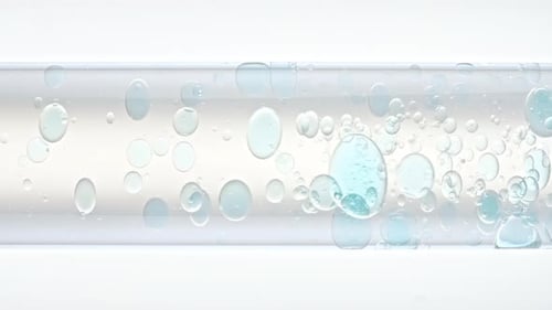 Feche as bolhas de ar azuis transparentes em água limpa subindo no tubo de ensaio de vidro branco