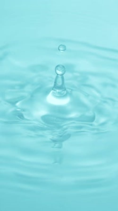Water Droplet Impacting Blue Surface and Creating Ripples