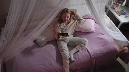 Girl Playing Game on Phone on Bed