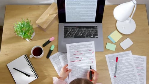 Top view of a woman working on a text to be translated. An editor marks words in a script.