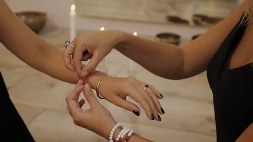 Woman Tying Red String Around Another Woman's Wrist