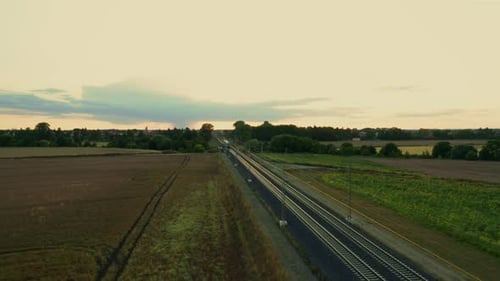 Blue Train with White Stripes Passes Through Rural Fields