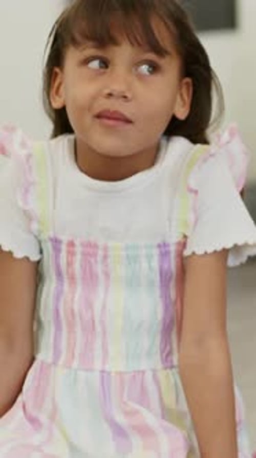 Vertical video: Hearing cue, girl in striped dress raising right arm to answer on bench with tablet