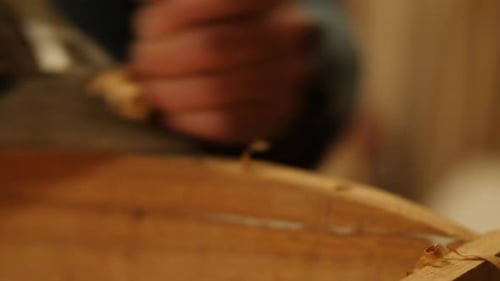 Close-up of a craftsman using a hand plane to smooth a wooden surface