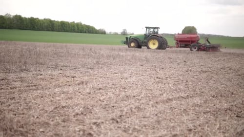 farmer watching his tractor planting sunflower at the field