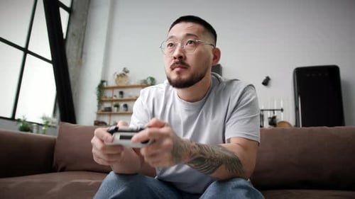 Man Plays Video Game on Couch at Home