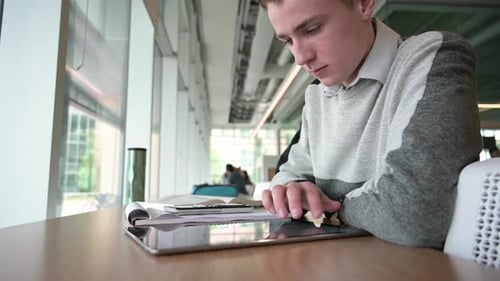 Focused student uses digital tablet touchscreen in university library